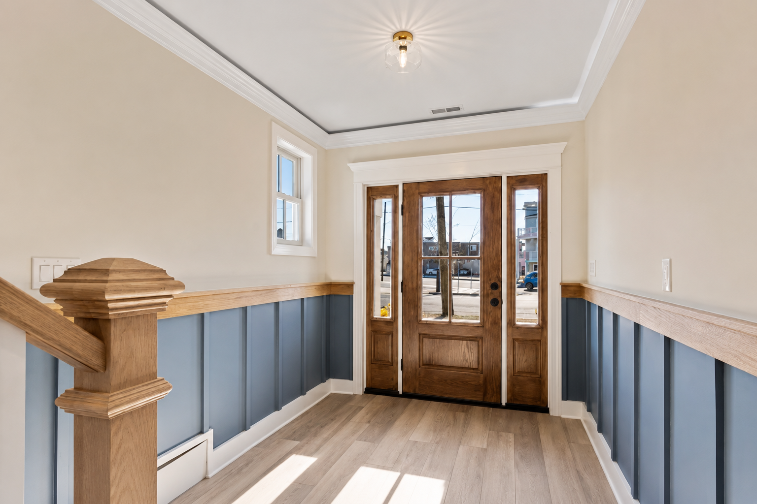Finished entry wall paneling with stair post and trim details