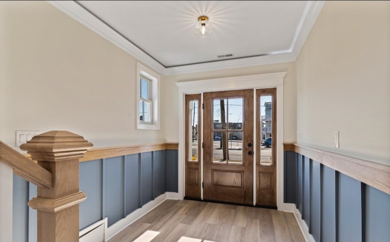Finished entry wall paneling with stair post and trim details
